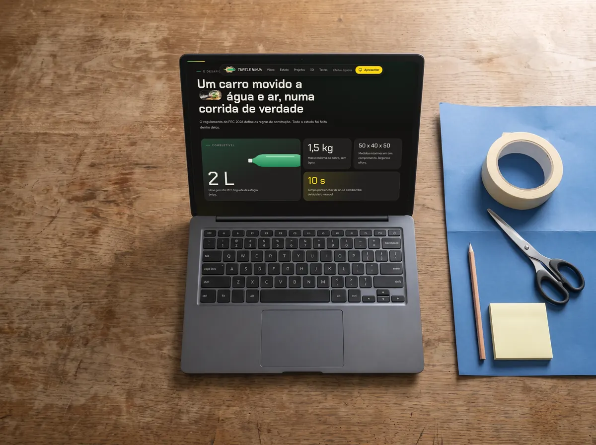 Mesa vista de cima com cartolina, fita, tesoura e um notebook com o site do carro de uma feira de ciências